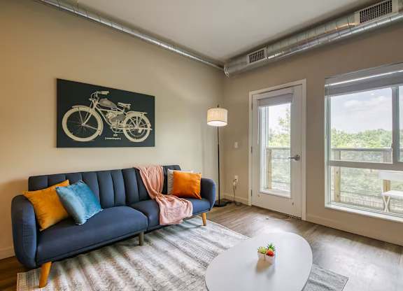 A living room with a blue couch and a bicycle picture on the wall.