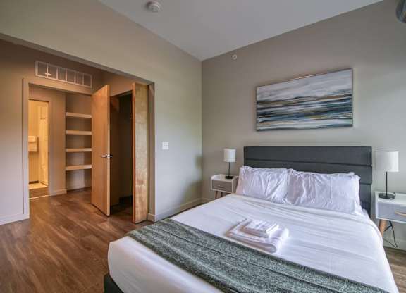 A bedroom with a large bed and a painting on the wall.