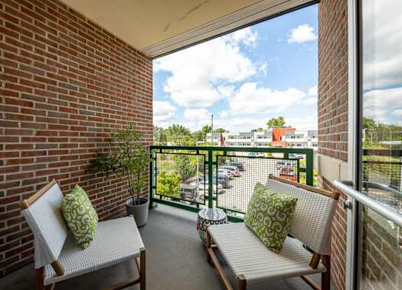 A balcony with two chairs and a table with a potted plant on it.