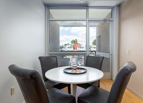A dining room with a table and chairs and a view of the outside.