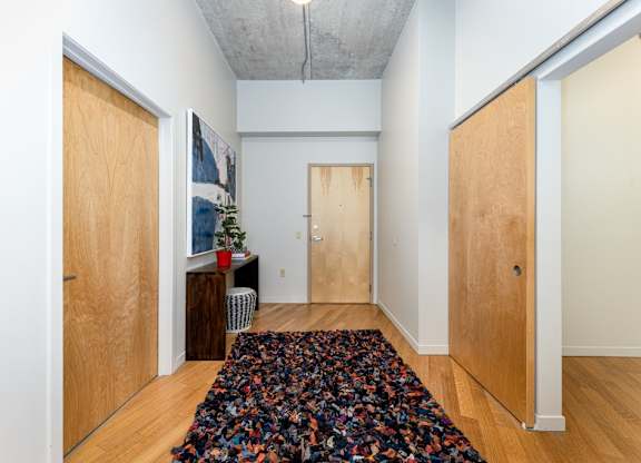 A hallway with a rug on the floor and two doors on either side.