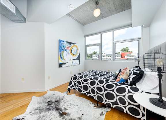 A bedroom with a bed, a rug, and a painting on the wall.