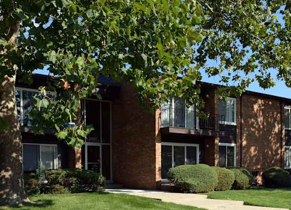 A building with a brick facade and a green lawn in front.