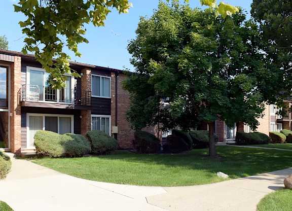 A tree in front of a building with a grassy area in front of it.
