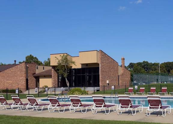 A poolside with chairs and a building in the background.