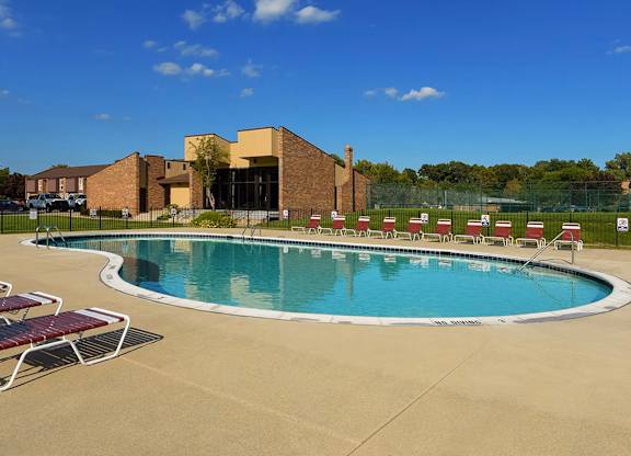A large outdoor swimming pool with sun loungers and a building in the background.