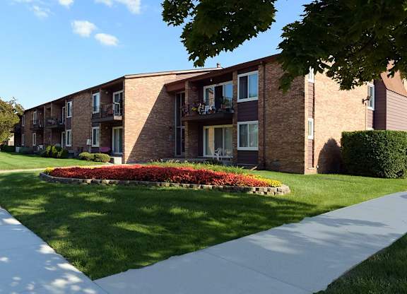 Apartment building with a flower bed in front.