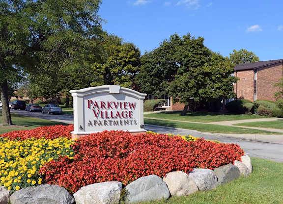 A sign for Parkview Village Apartments is surrounded by a flower bed.