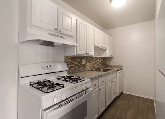 A kitchen with white cabinets and a white stove top oven.