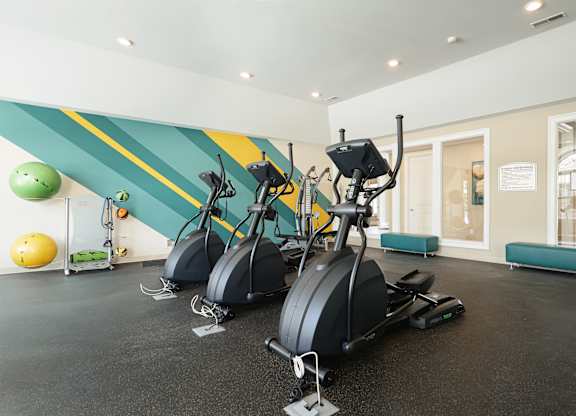A gym with exercise equipment and a green ball.