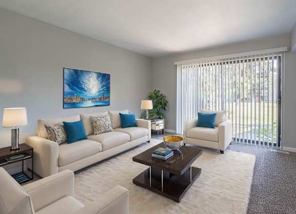 A living room with a white couch, a coffee table, and a painting on the wall.