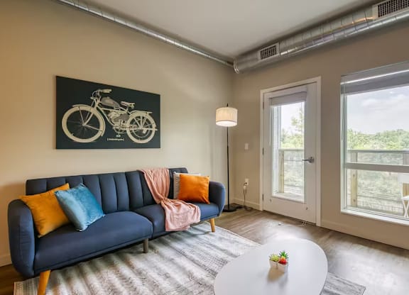 A living room with a blue couch and a motorcycle picture on the wall.