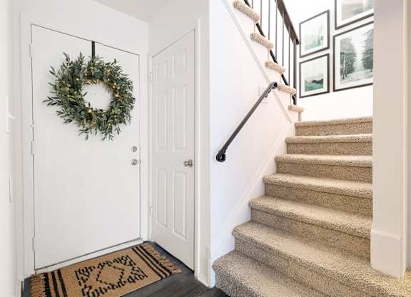 A white door with a wreath on it and a staircase.