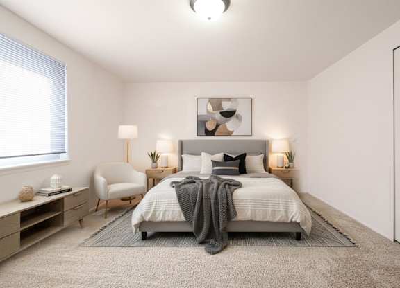 A bedroom with a bed, chair, and nightstands.