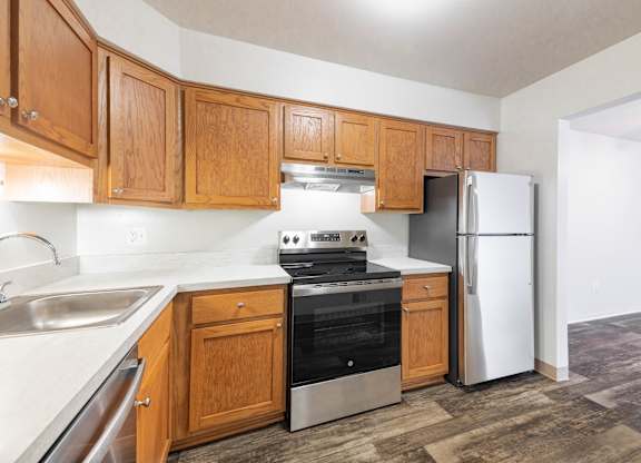 A kitchen with wooden cabinets and a stainless steel refrigerator.