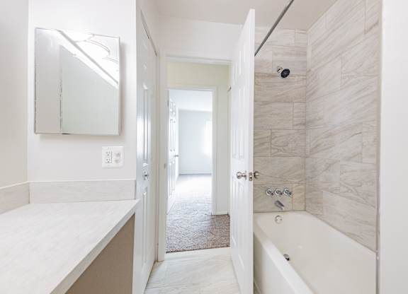 A bathroom with a tub and a mirror.