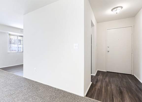 A room with a white door and a window with a view of a building outside.