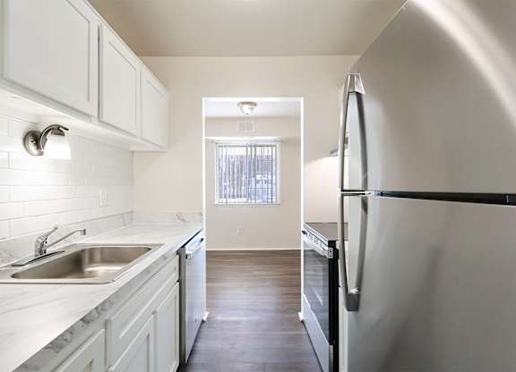 A kitchen with white cabinets and a black fridge.