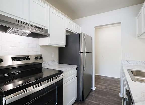 A kitchen with a black fridge and stove top oven.