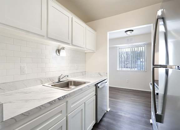 A kitchen with white cabinets and a marble countertop.