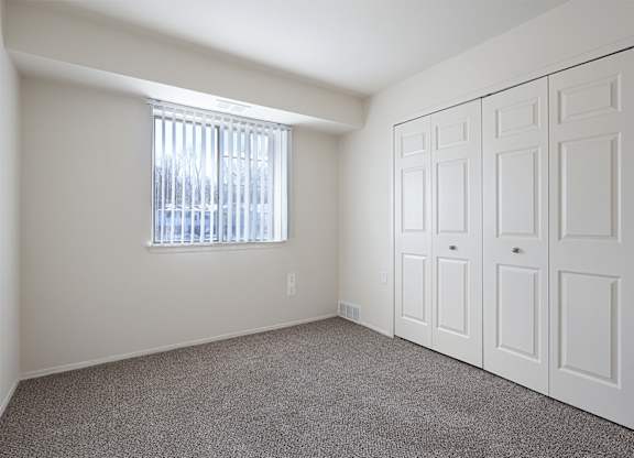A room with a window and a set of white doors.
