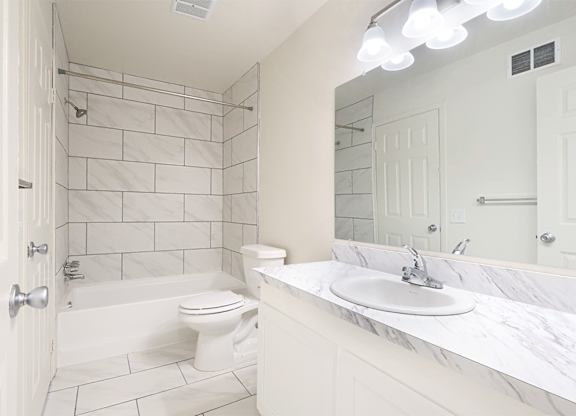 A white bathroom with a toilet, sink, and shower.