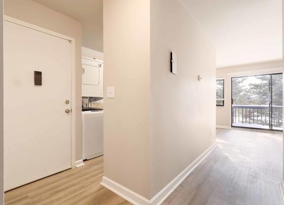 A white door is on the left and a white washer and dryer are in the corner.