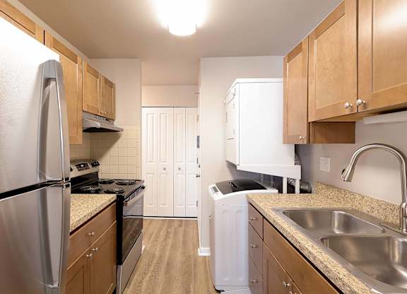 A kitchen with a refrigerator, sink, and cabinets.