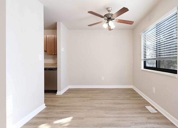 A room with a ceiling fan and a window with blinds.