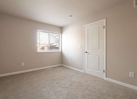 A room with a carpeted floor and a window with blinds.