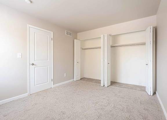 A room with a white door and a white closet with a white door.