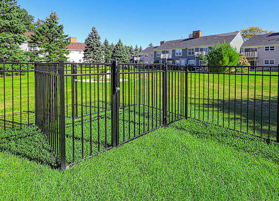 A black metal fence in front of a green lawn.