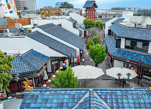 A view of a courtyard with a white umbrella and a blue building.