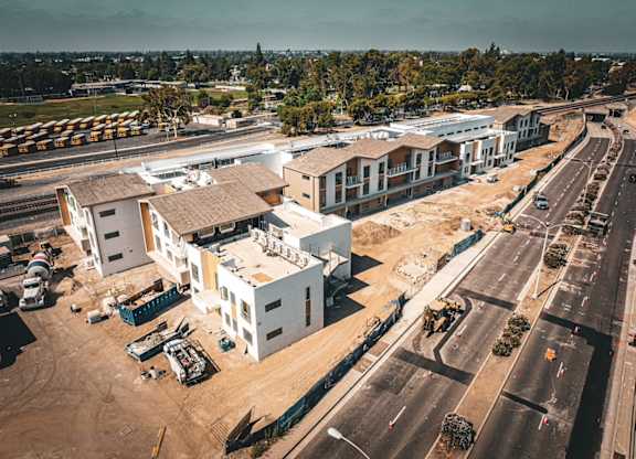 A construction site with unfinished buildings and a road in front.