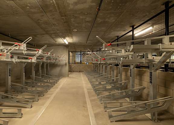 A long row of bike racks are lined up in a concrete room.