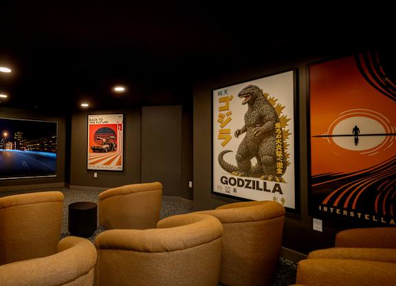 A room with a screen, chairs and posters of Godzilla.