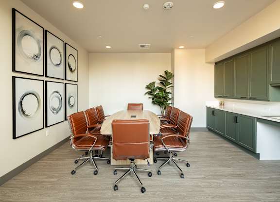 A conference room with a table surrounded by chairs and pictures on the wall.