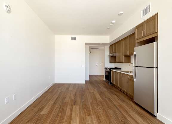 A kitchen with a refrigerator, sink, and wooden floors.