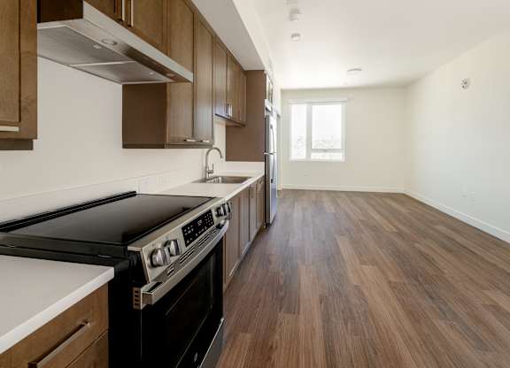 A kitchen with wooden floors and a stove top oven.