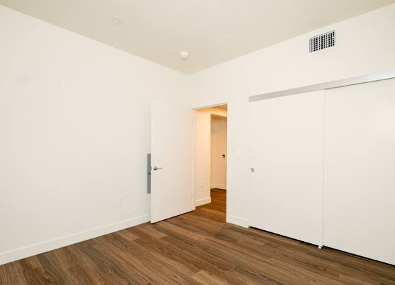 A white door is open to a hallway with wood floors.