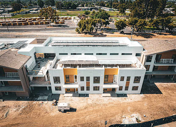 A large white building with a yellow section in the middle is under construction.
