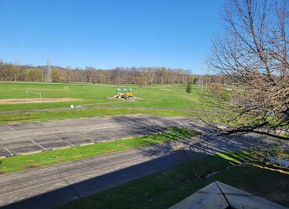 A park with a playground and a paved area.