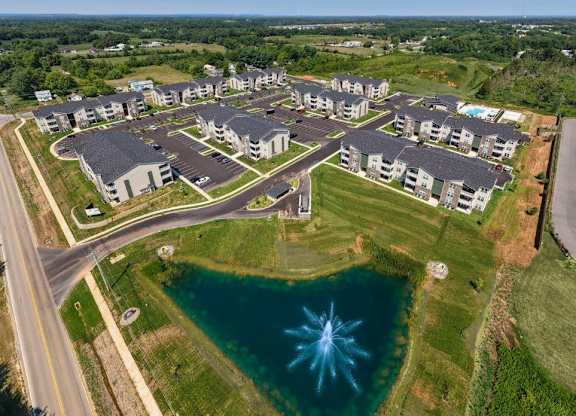 A bird's eye view of a housing complex with a pond in the foreground.