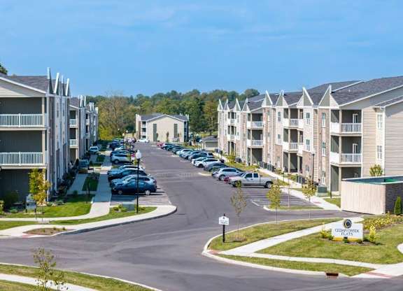 A row of apartment buildings with cars parked in front.
