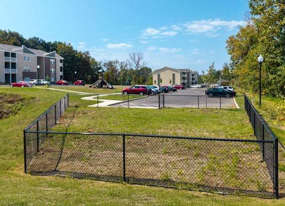 A black fence surrounds a grassy area with a building in the background.