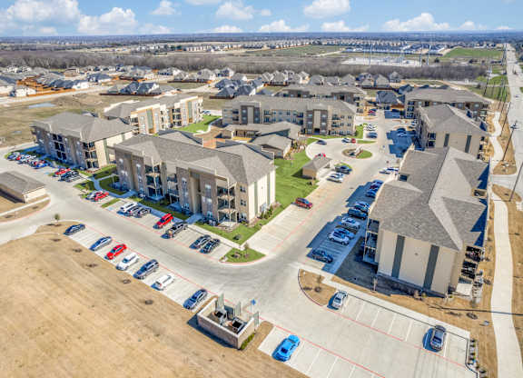 A large apartment complex with a parking lot in front.