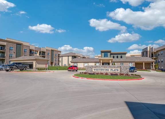 A parking lot in front of a building named Whitewing Flats.