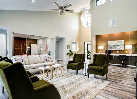 A living room with a white couch, a green chair, and a wooden floor.