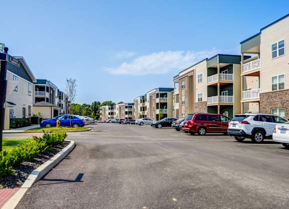 A parking lot with cars and apartment buildings in the background.