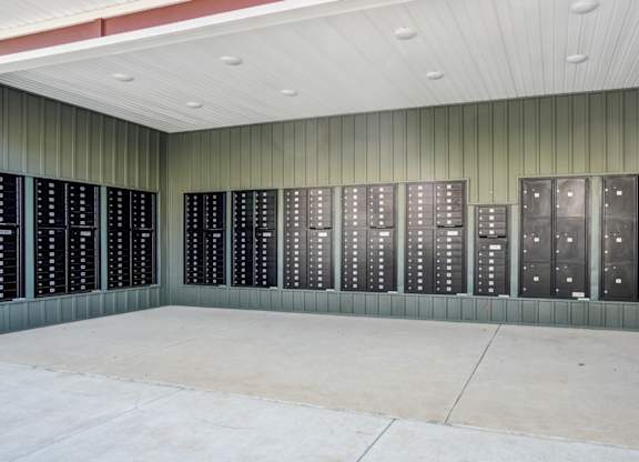 A wall of black lockers in a room with a concrete floor.
